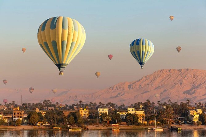 Hot air balloons rising at sunrise over the Nile and the West Bank hills of Luxor, Egypt